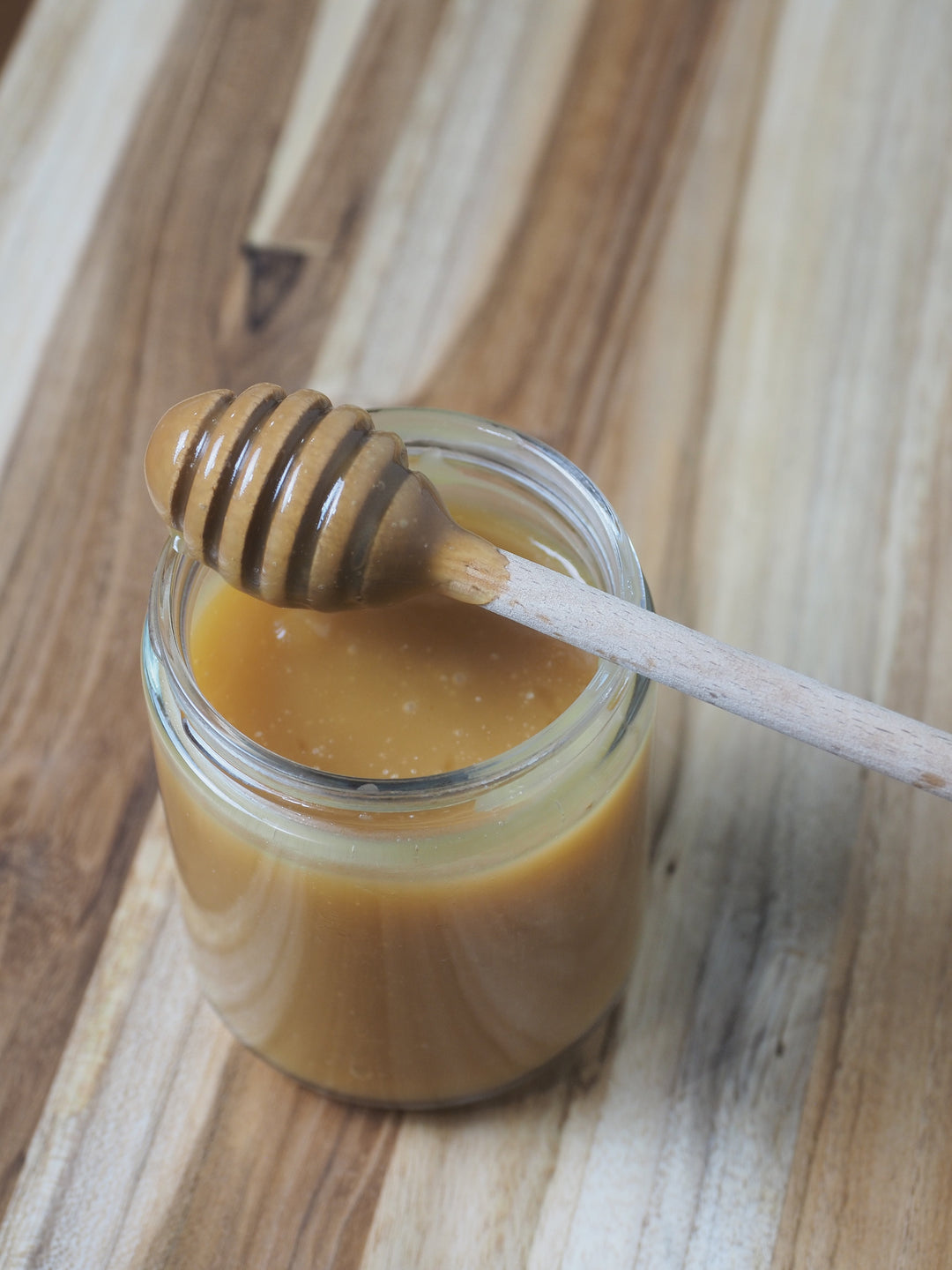 Honey comb stick on top of jar full of Bee Mafia Honey Caramel