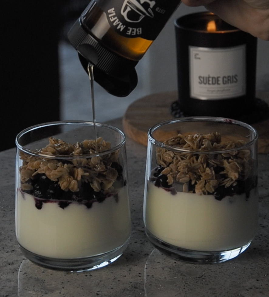 Bee Mafia Cinnamon Honey drizzled on top of two yogurt bowls in glass cups.