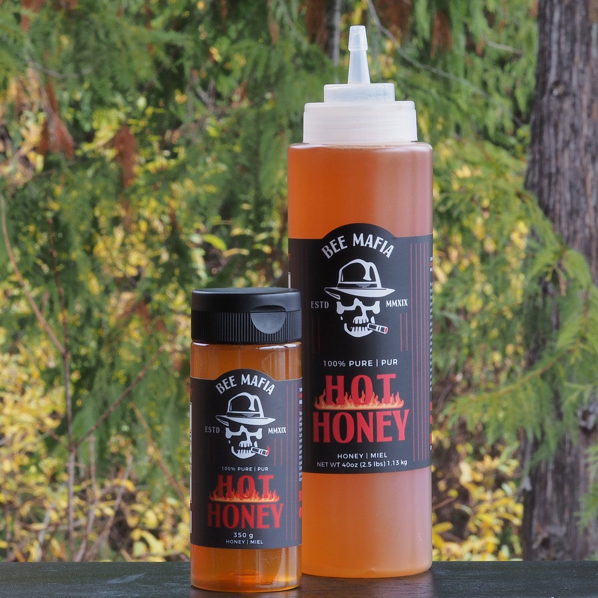 Combination pack of Bee Mafia Hot Honey products. Larger and smaller bottle with trees in the background. Product of Canada.